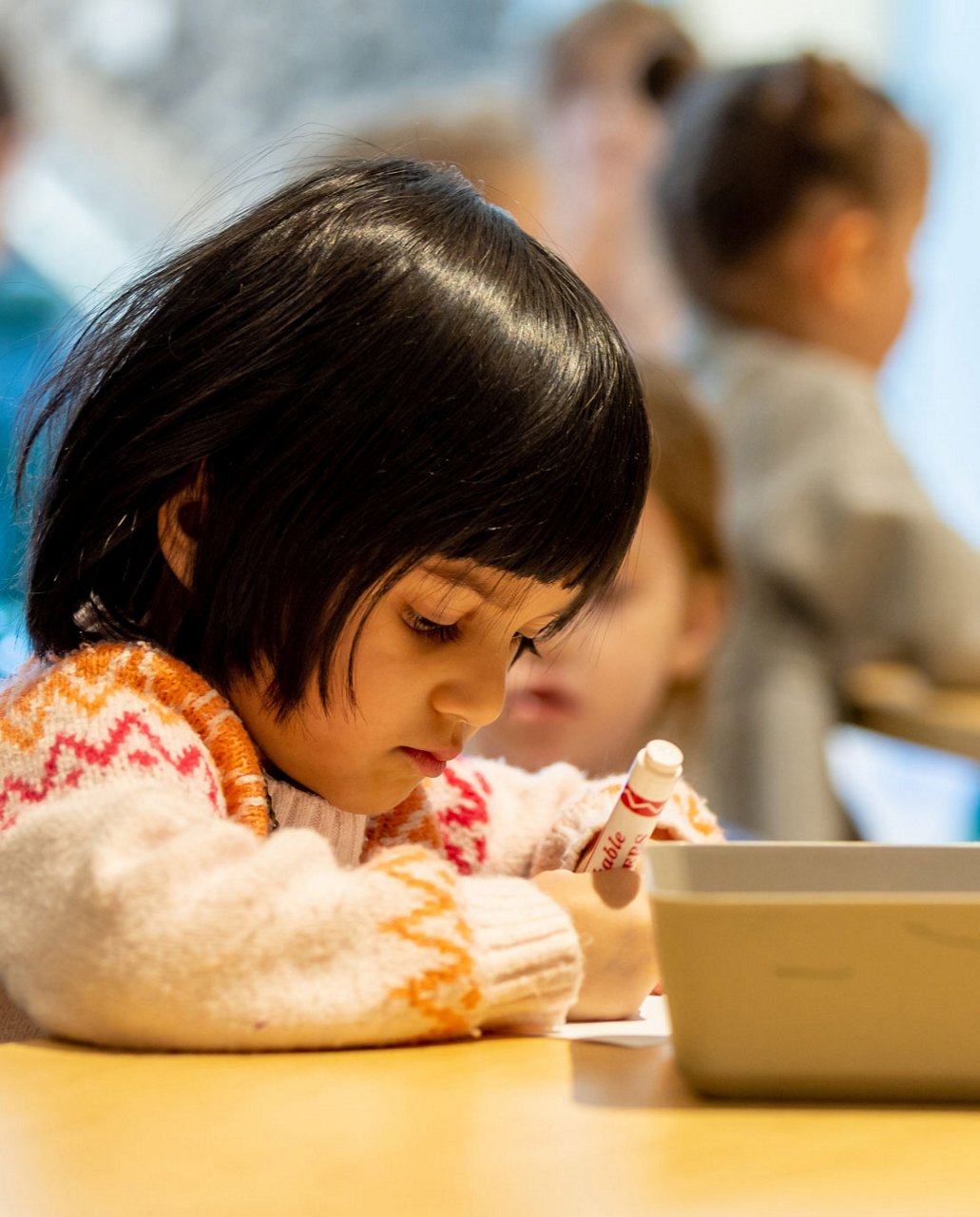 A child lying on the ground writing with a pencil 