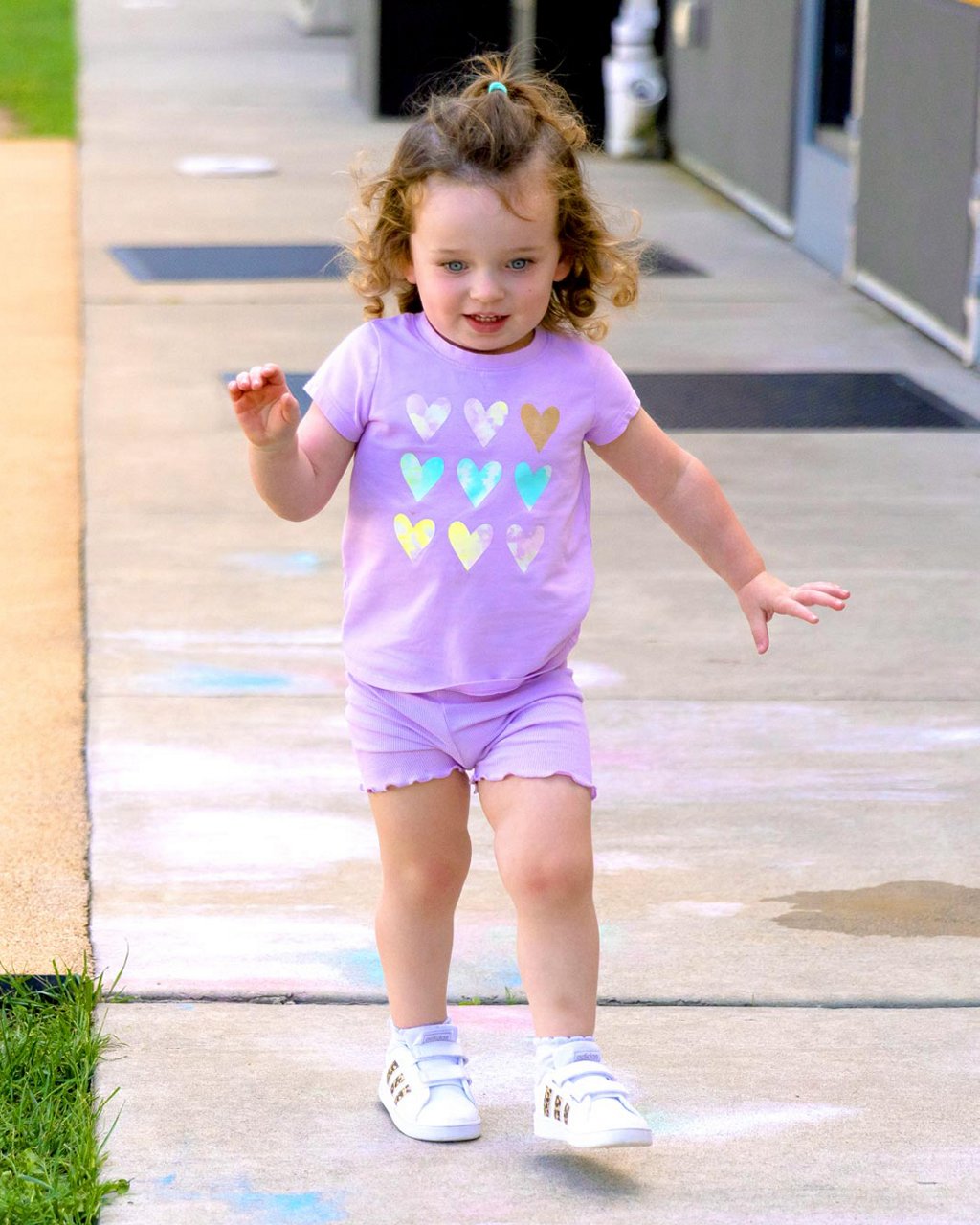 A child playing with sidewalk chalk on a playground