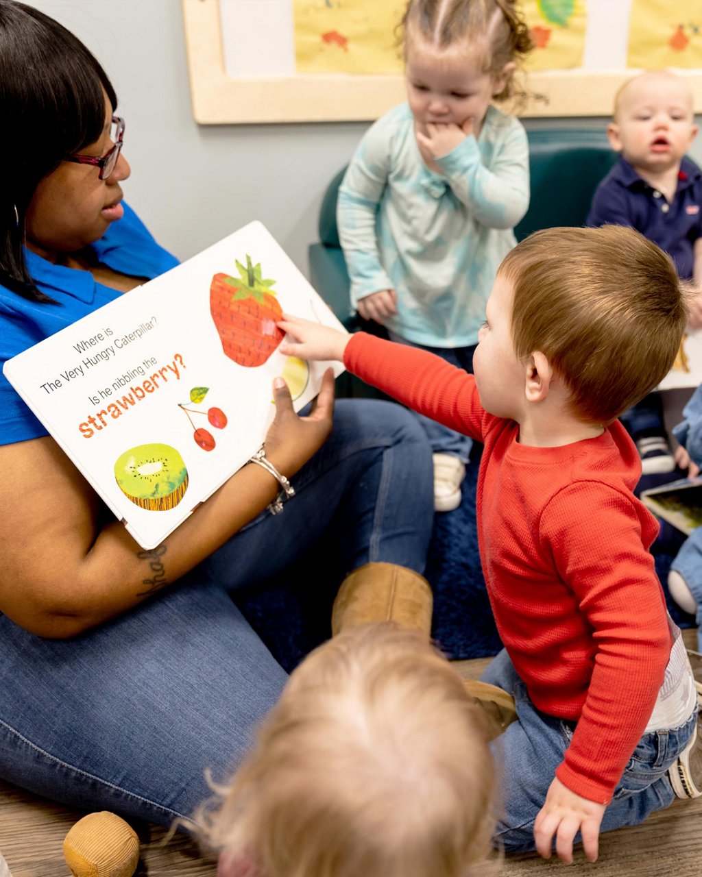 A teacher reading a book to children 