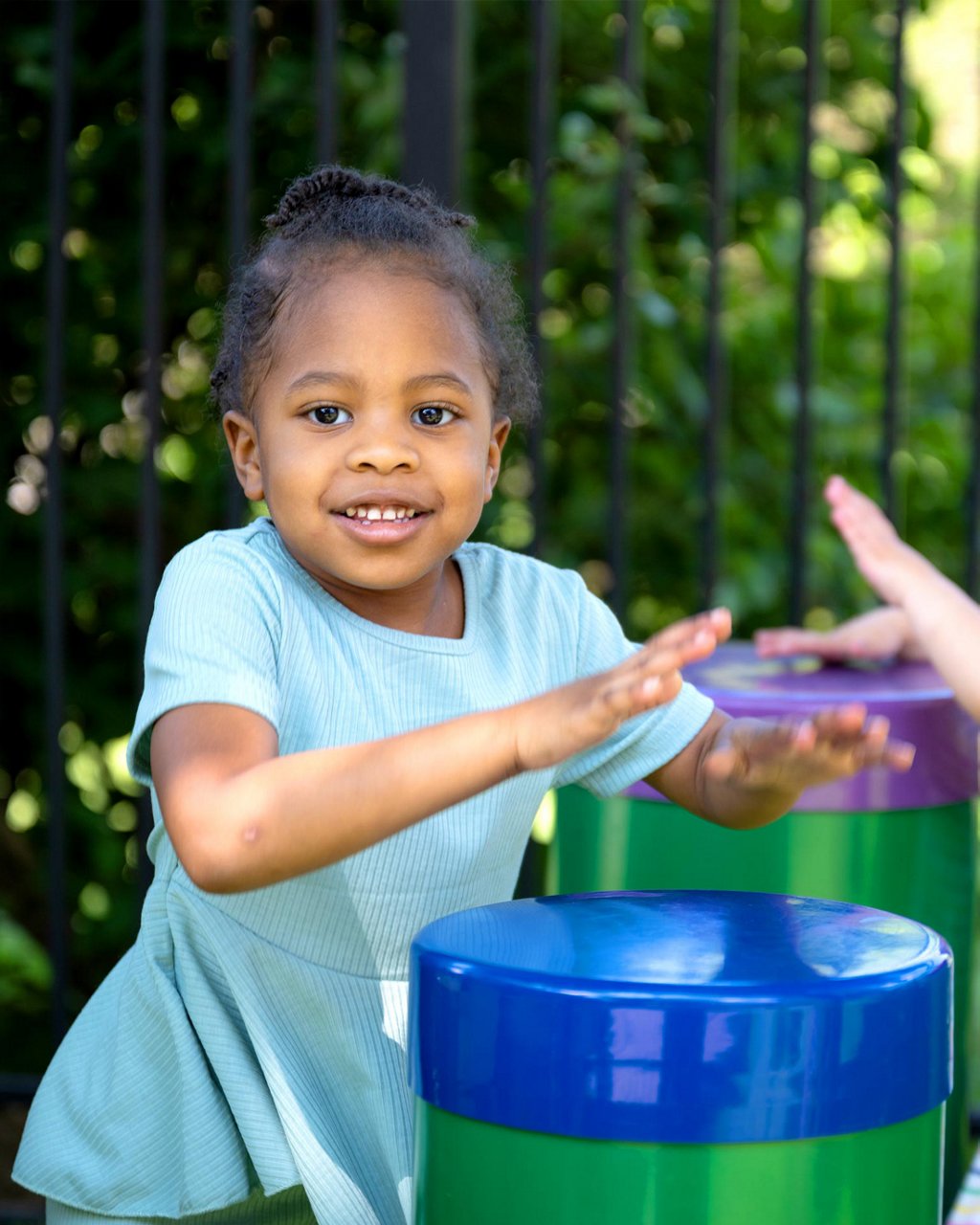 A child playing drums in an outdoor classroom