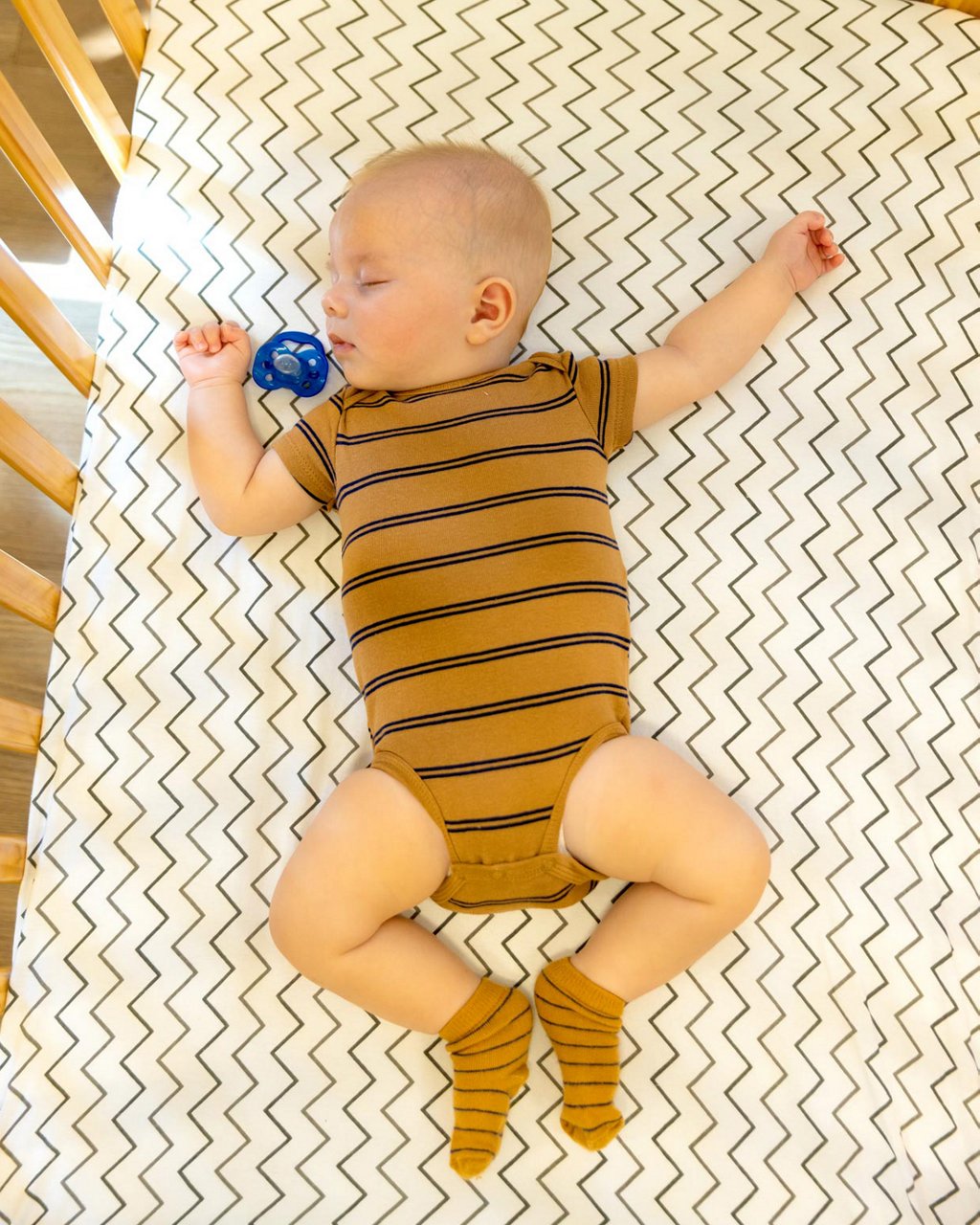 A child napping on their back in a crib.