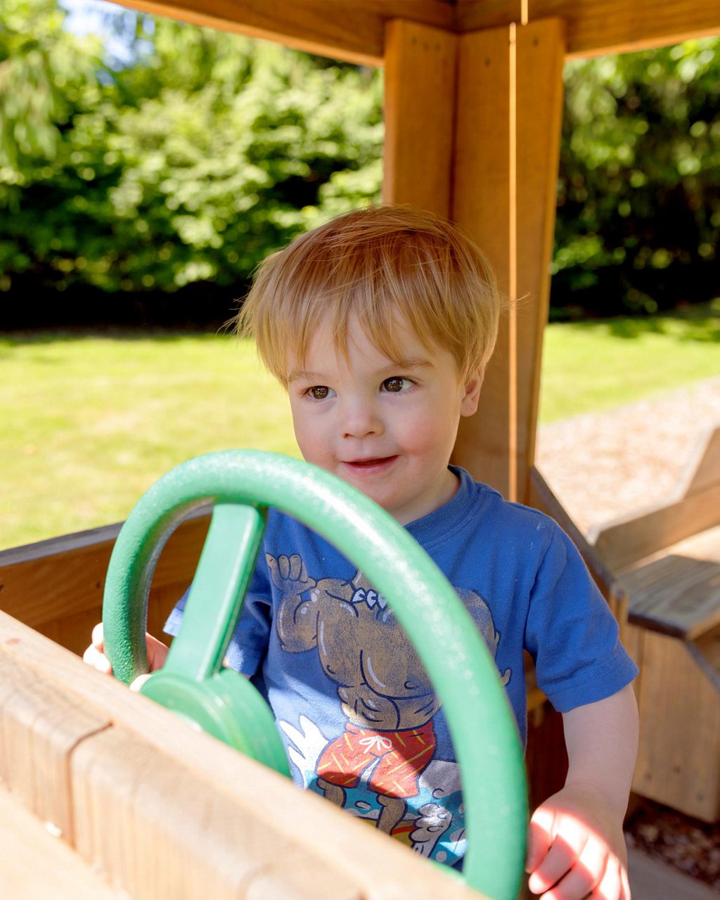 A child playing in a pretend car on a playground 