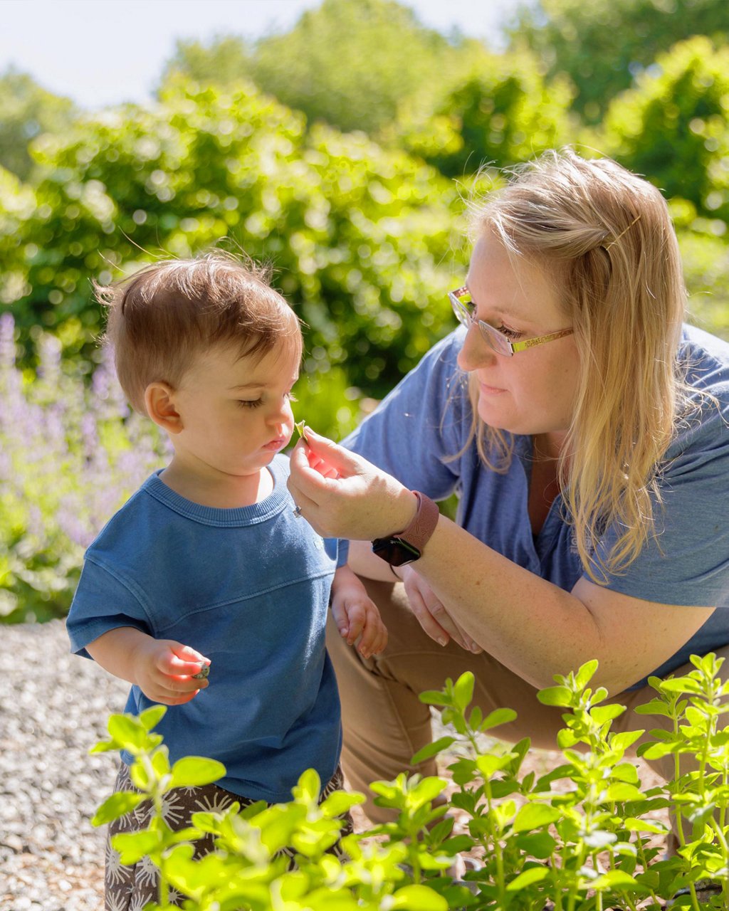 A child and teacher exploring plants in a garden 