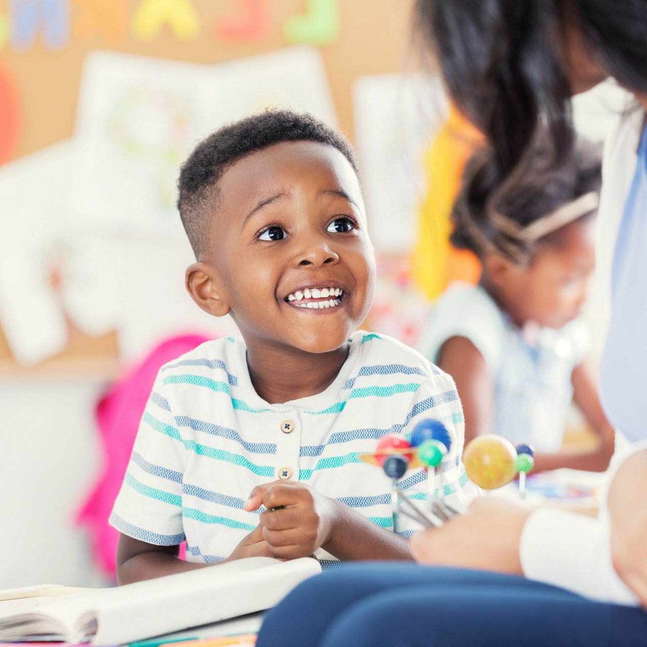 Preschool boy smiling at his teacher in a preschool classroom