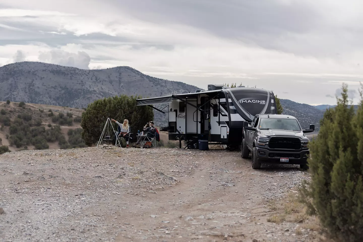 Campers sitting in front of a Grand Design Imagine with the mountains in the background. 