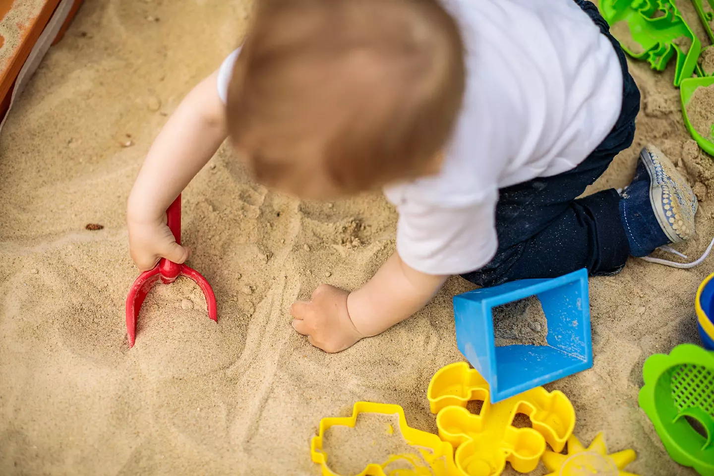 Child playing in sand with sand toys