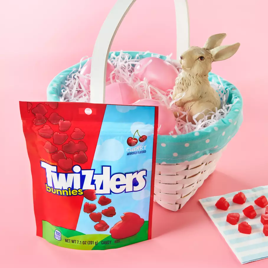 bag of twizzlers easter bunnies cherry candy beside easter basket filled with plastic eggs