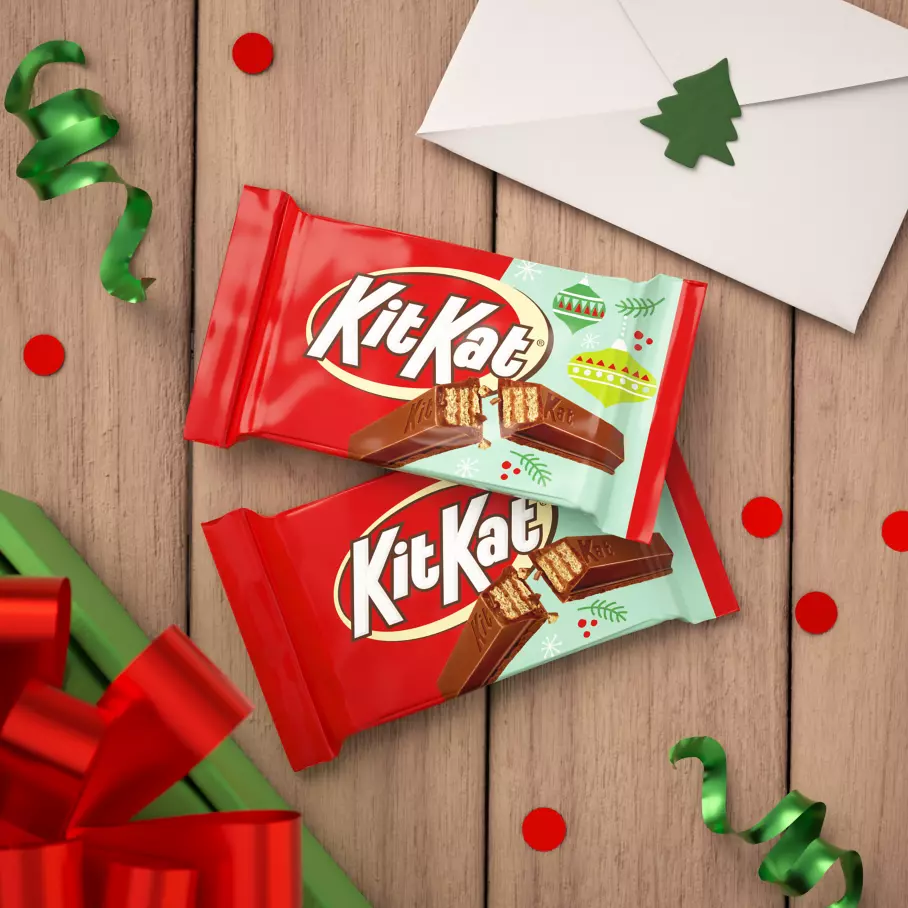 packs of kit kat holiday milk chocolate candy bars beside holiday gifts