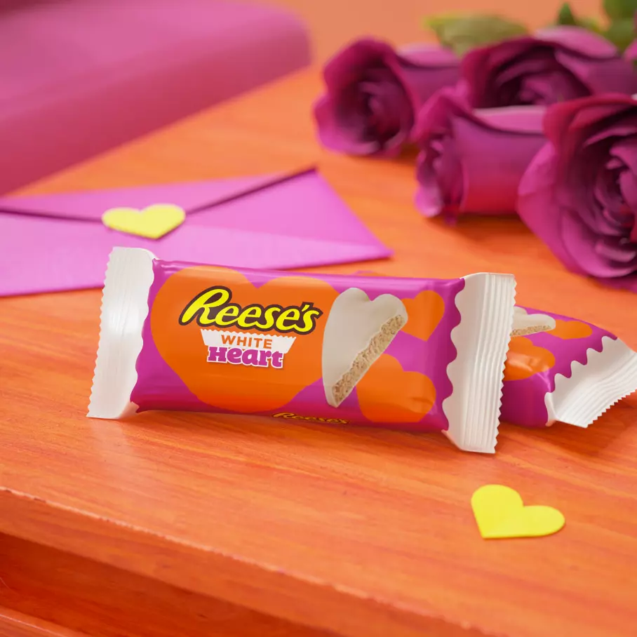 packs of reeses white creme peanut butter hearts beside roses and cards