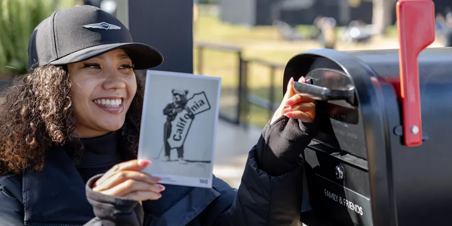 Attendee with Genesis cap on placing postcard into mailbox at 2026 Genesis Invitational