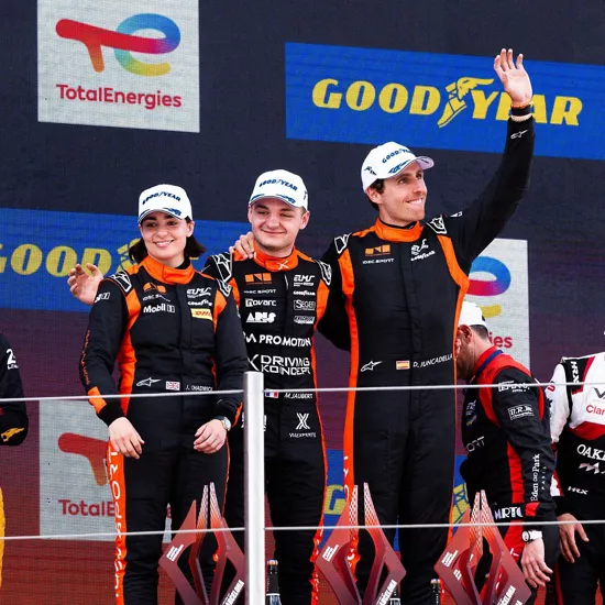 Three Genesis Magma Racing driver standing atop first-place podium in celebration