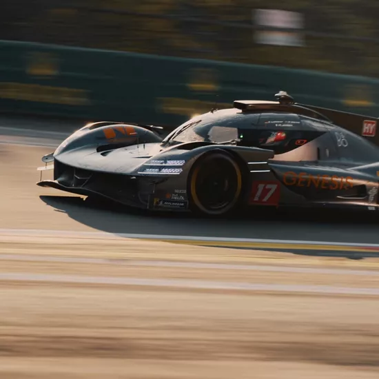 Driver-side close-up of Genesis GMR-001 Hypercar in black, driving along race track