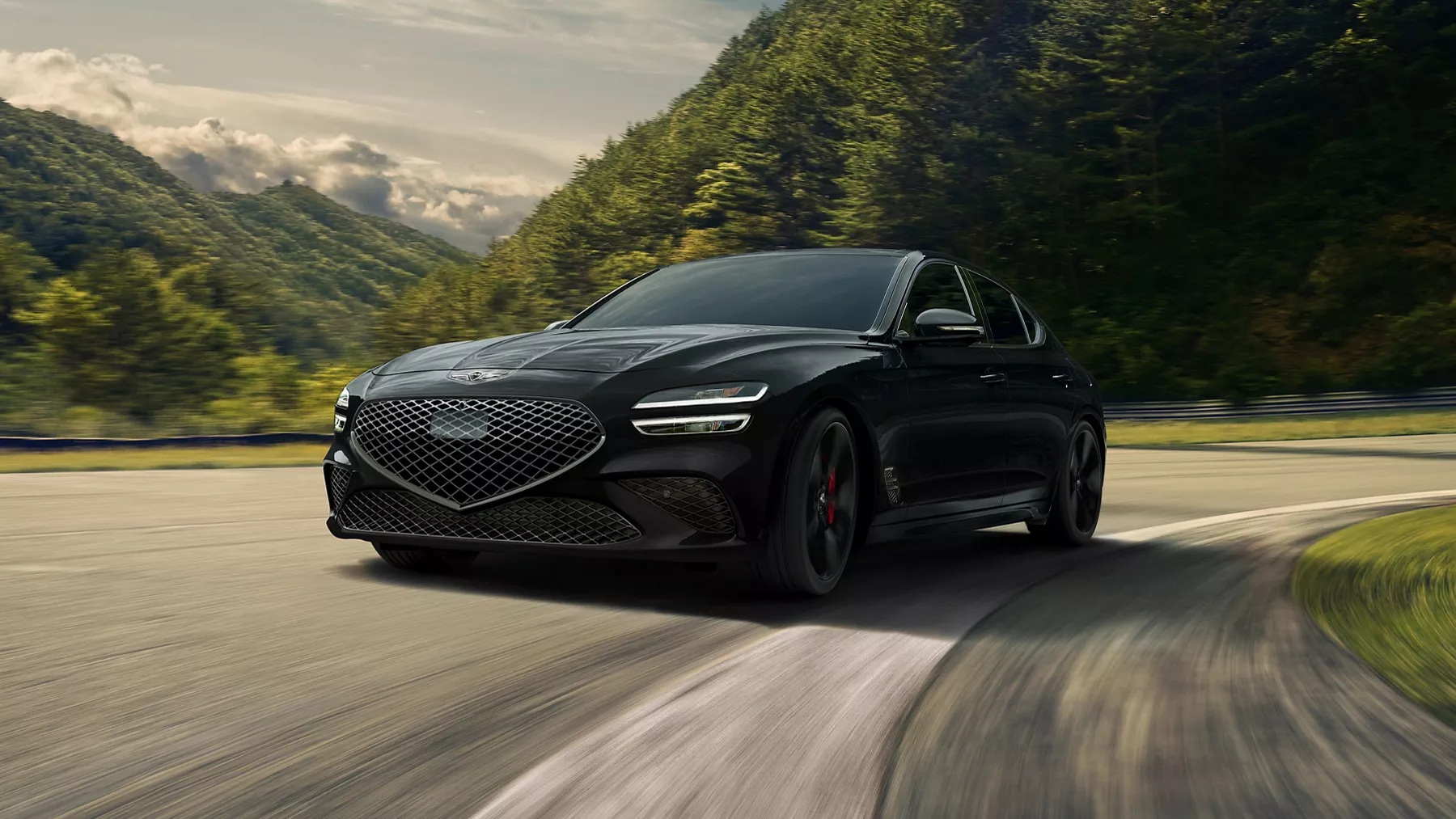 3/4 driver side view of 2027 Genesis G70 in Vik Black​ in motion, driving along mountain road