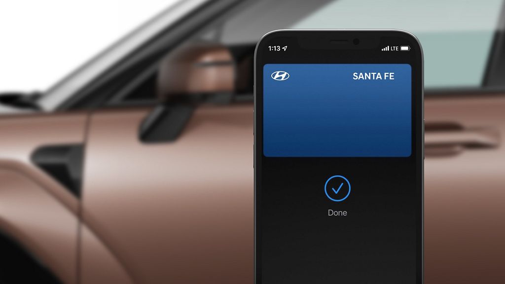 Smartphone showing a Santa Fe digital key card with a Done check mark, in front of a Hyundai Santa Fe door