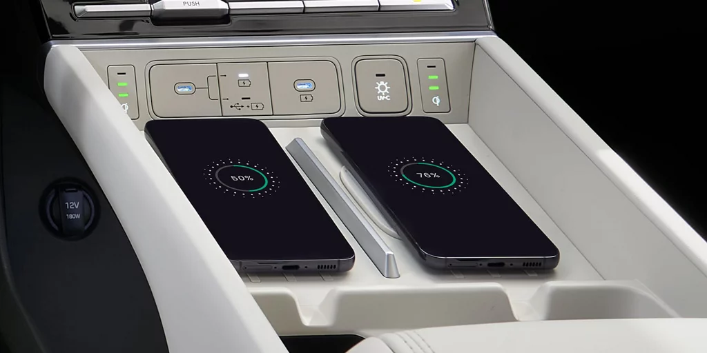 Two phones resting on adjacent wireless charging pads in a Hyundai Santa Fe center console