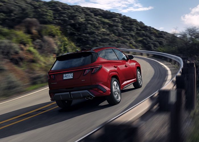 2025 Tucson Hybrid rear 3/4 view driving.