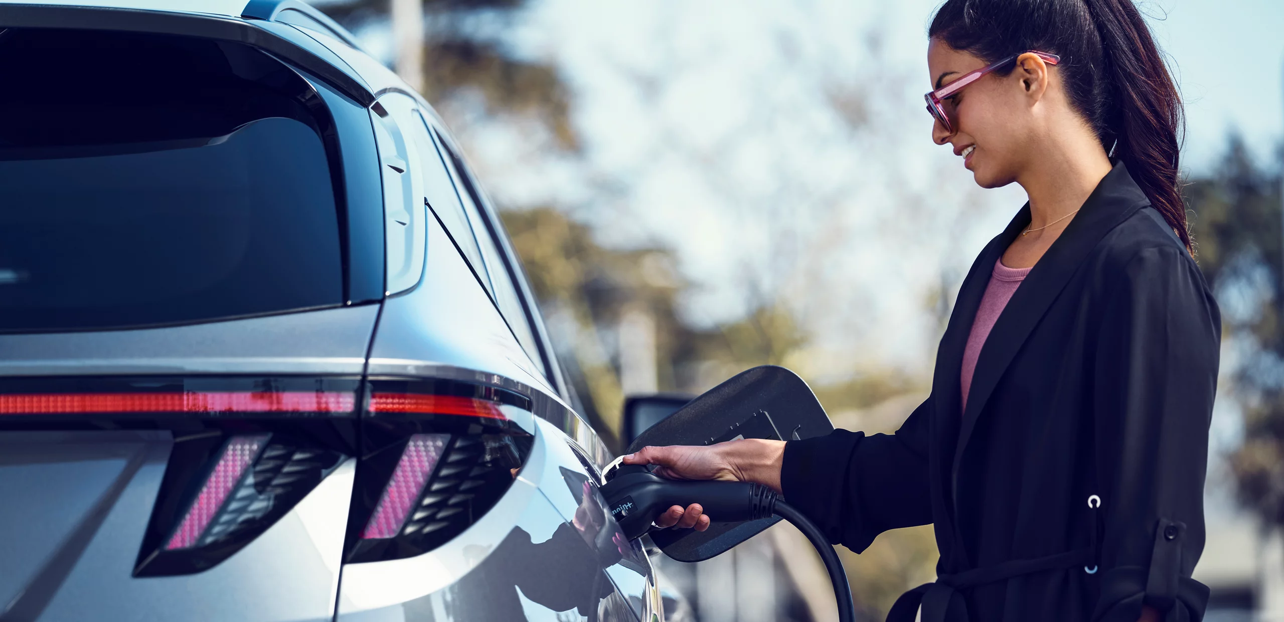 Woman charging a new 2026 Hyundai Tucson Hybrid car