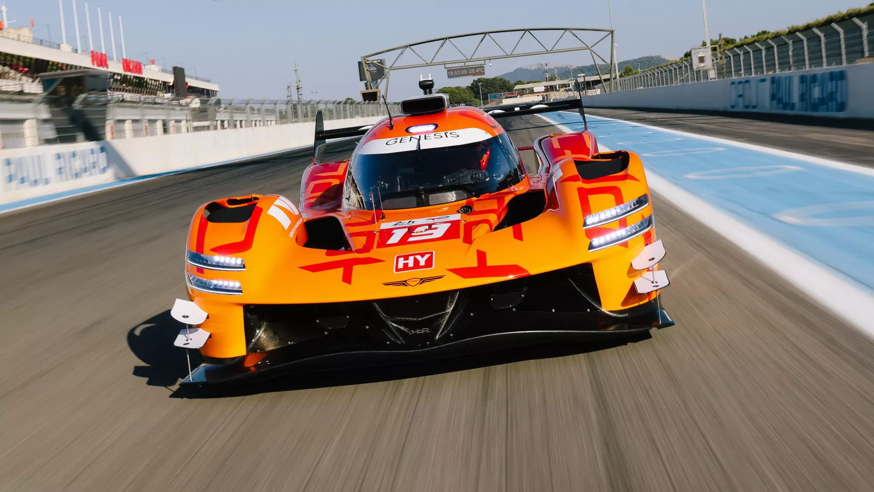 Front facing view of Genesis Magma Racing's GMR-001 Hypercar in Magma Orange driving on a race track