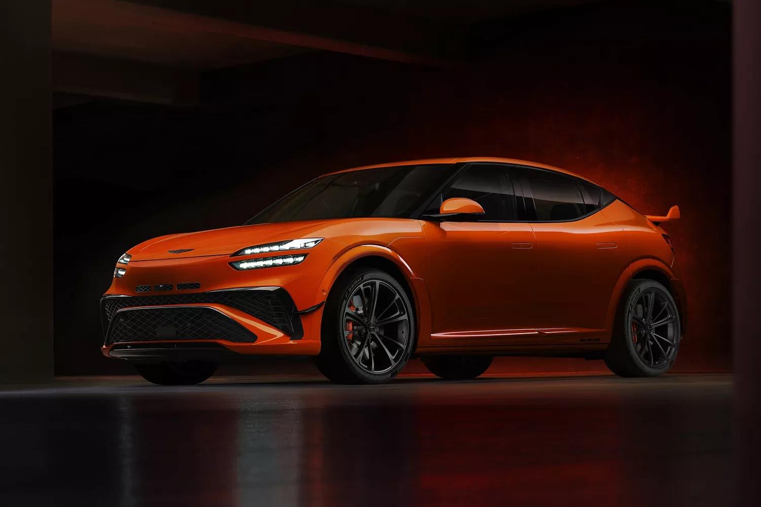 3/4 driver side view of 2027 Genesis GV60 Magma in orange, parked in dimly lit building
