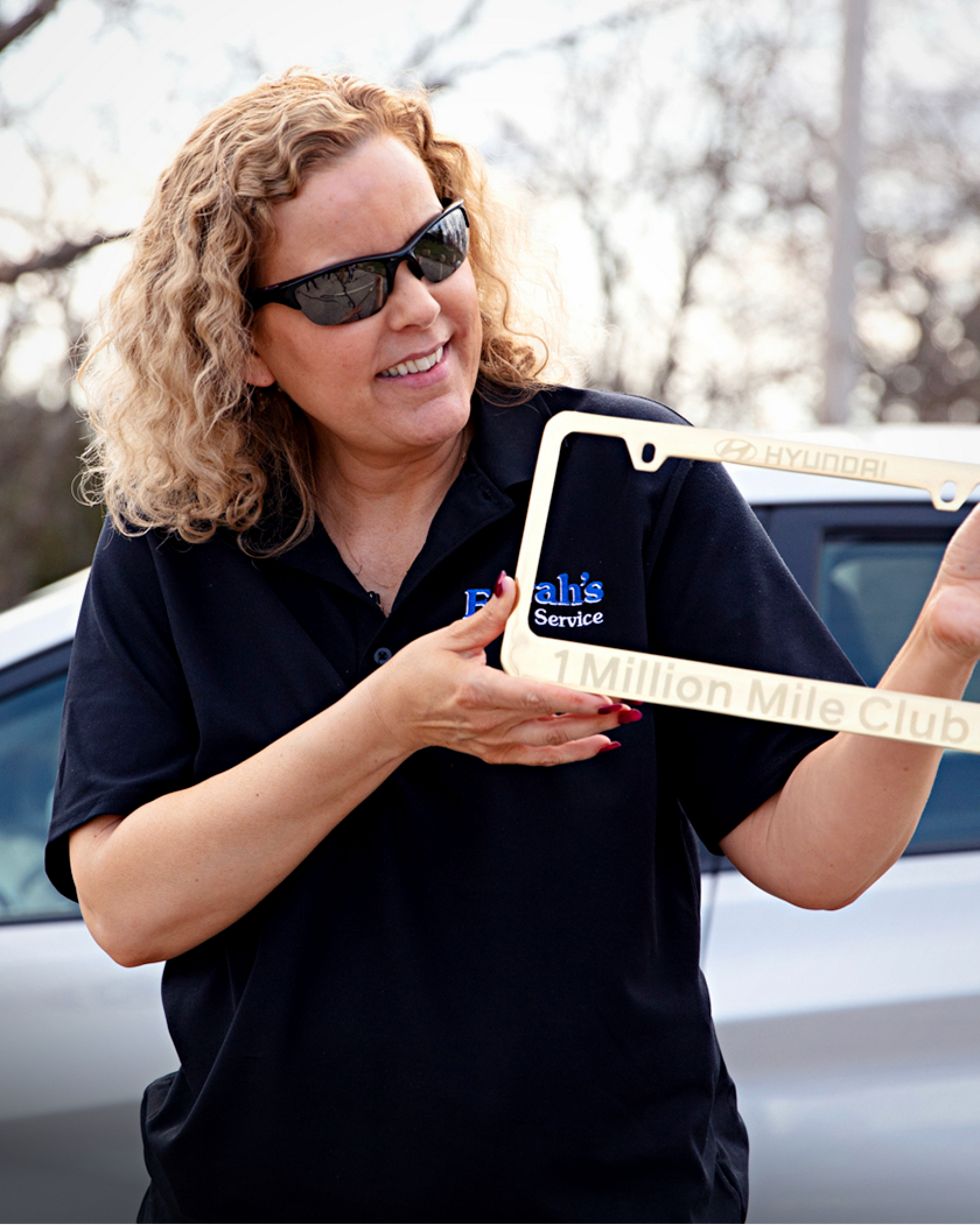 Farrah Haines holds up her Million Mile Club license plate frame