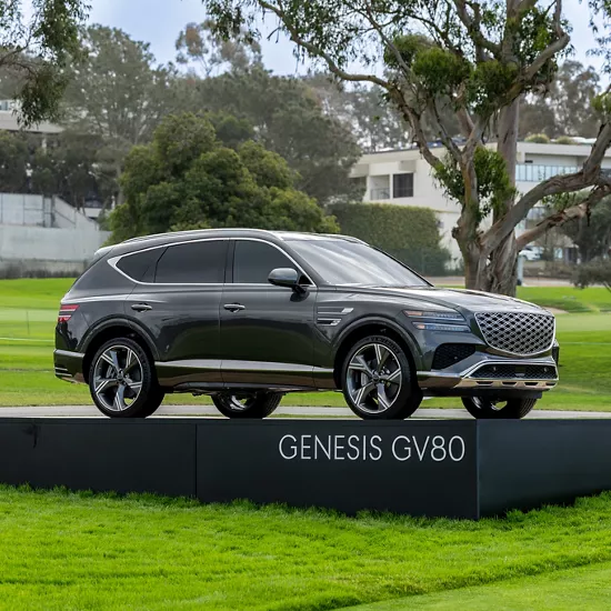 7/8 passenger side profile of Genesis GV80 on a platform on the golf course for Genesis Invitational