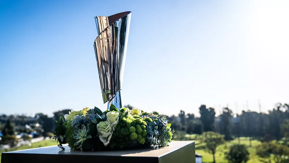 Genesis Invitational Trophy on a stand, flowers around the base, with golf course in the background