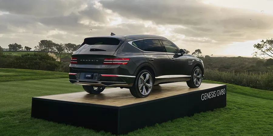 Rear 7/8 angle of Genesis GV80 in Makalu Gray atop a platform display at 2025 Genesis Invitational