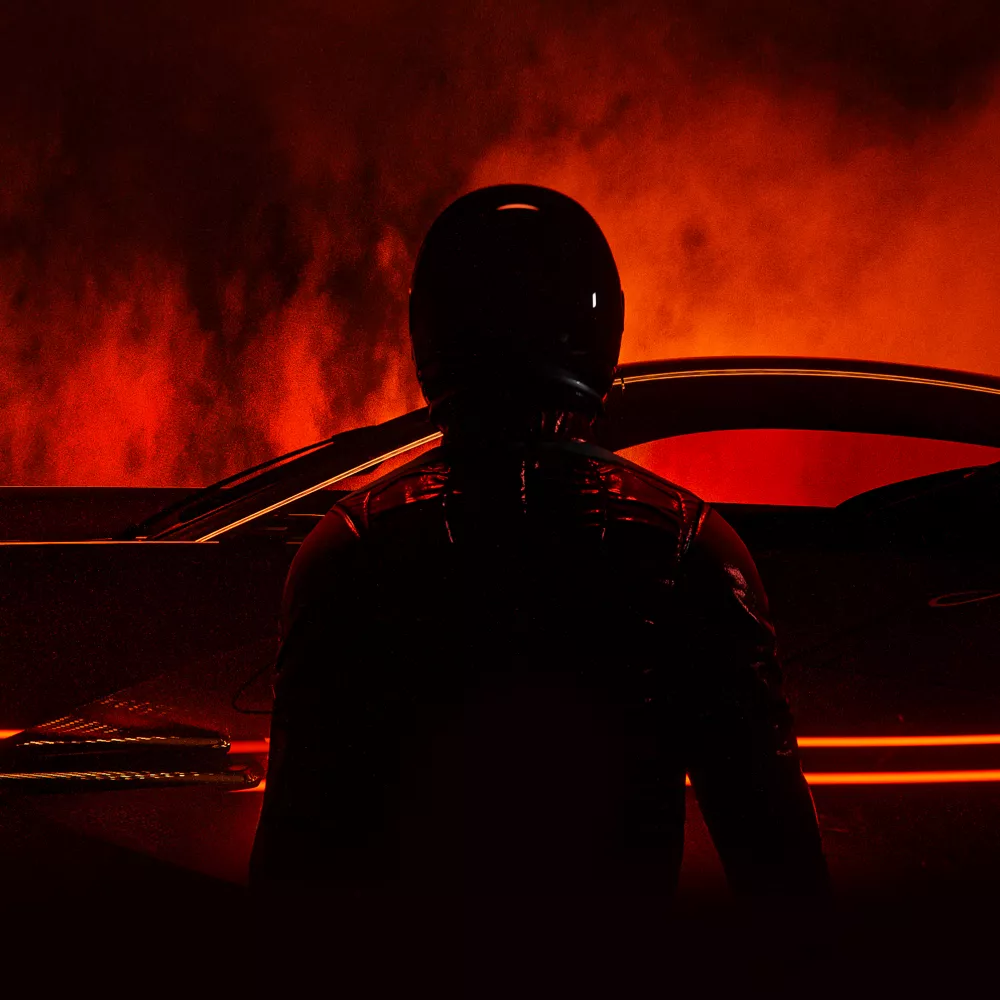 Silhouette of driver with helmet in front of red background