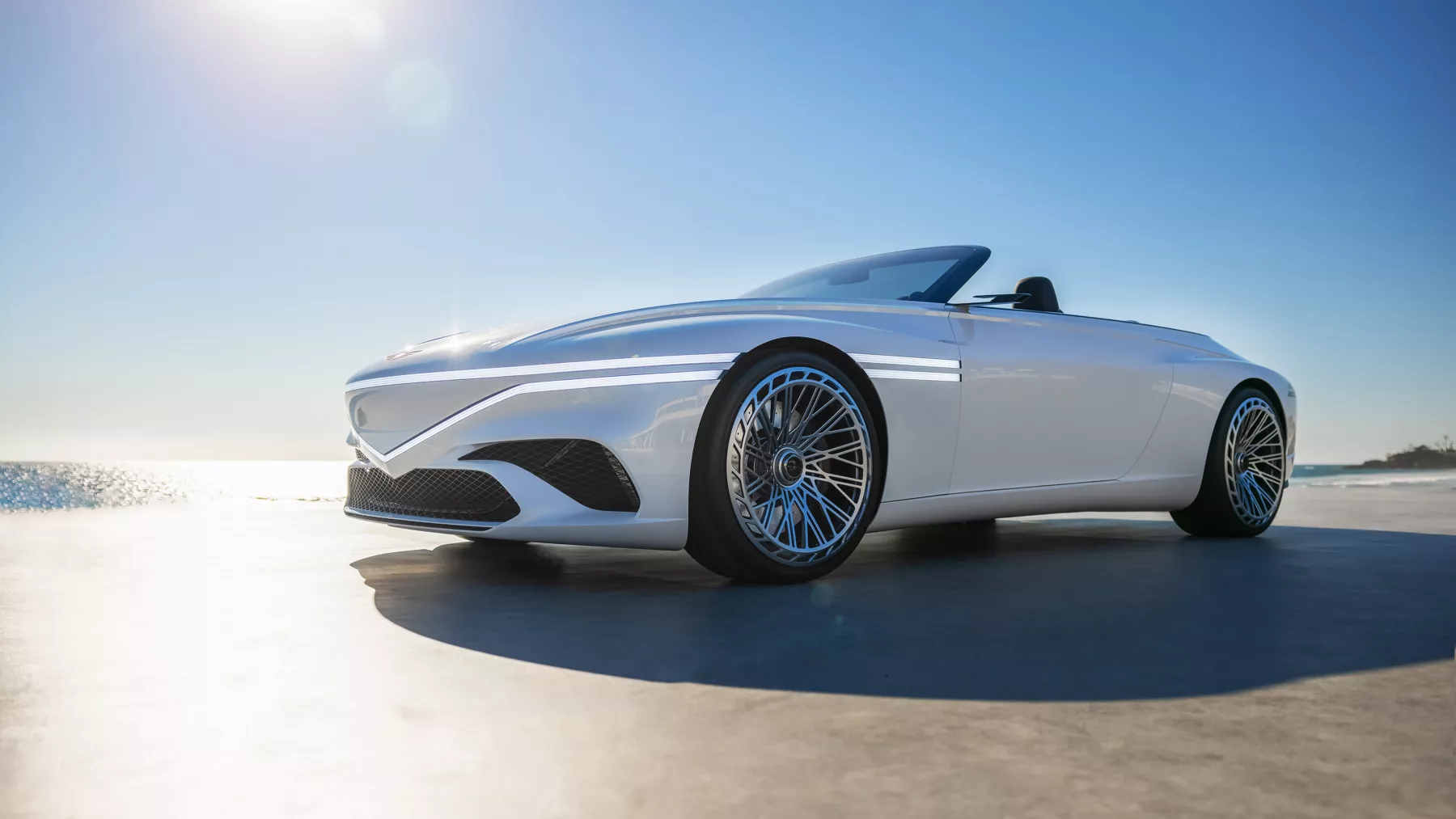 X Convertible Concept parked on a beach with an ocean and sunset in the background.