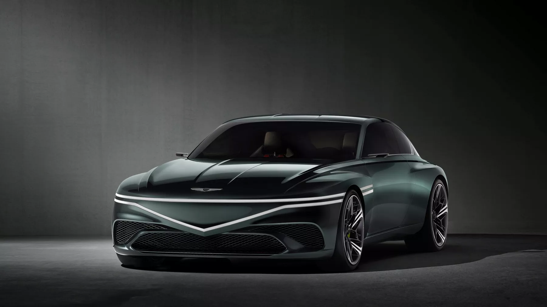 Front profile of X Speedium Coupe Concept with headlights illuminated.