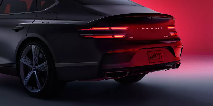 G80 rear tail lights and trunk parked in front of a red background.