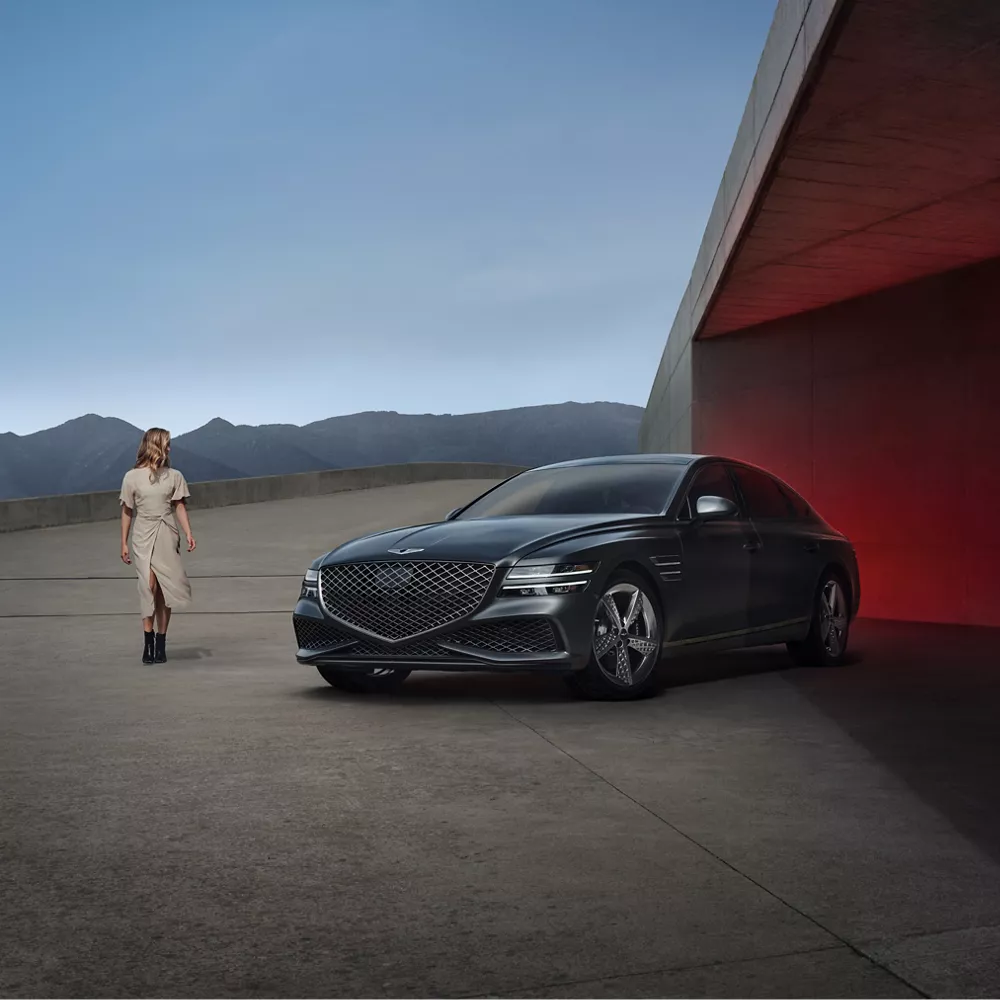 Woman standing next to G80 parked in the desert.