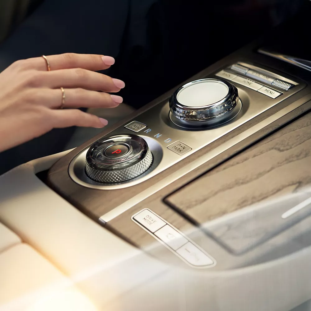 Human hand adjusting dial on G80 center console.