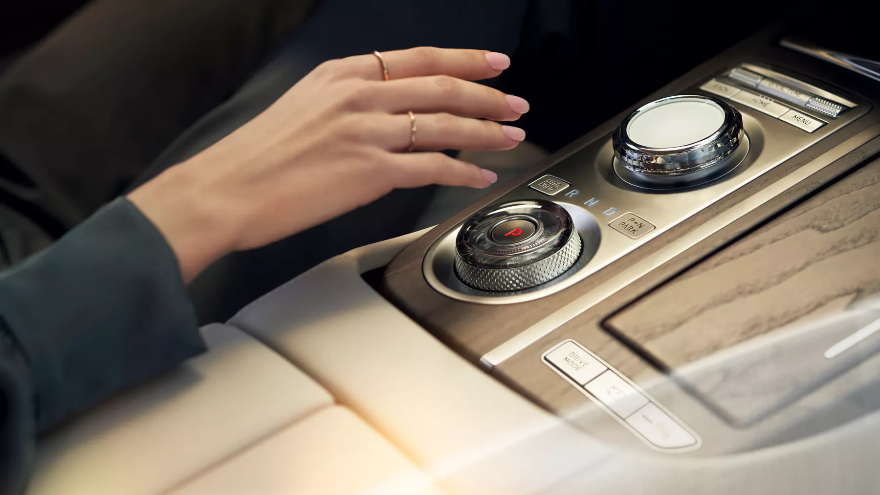 Human hand adjusting dial on G80 center console.