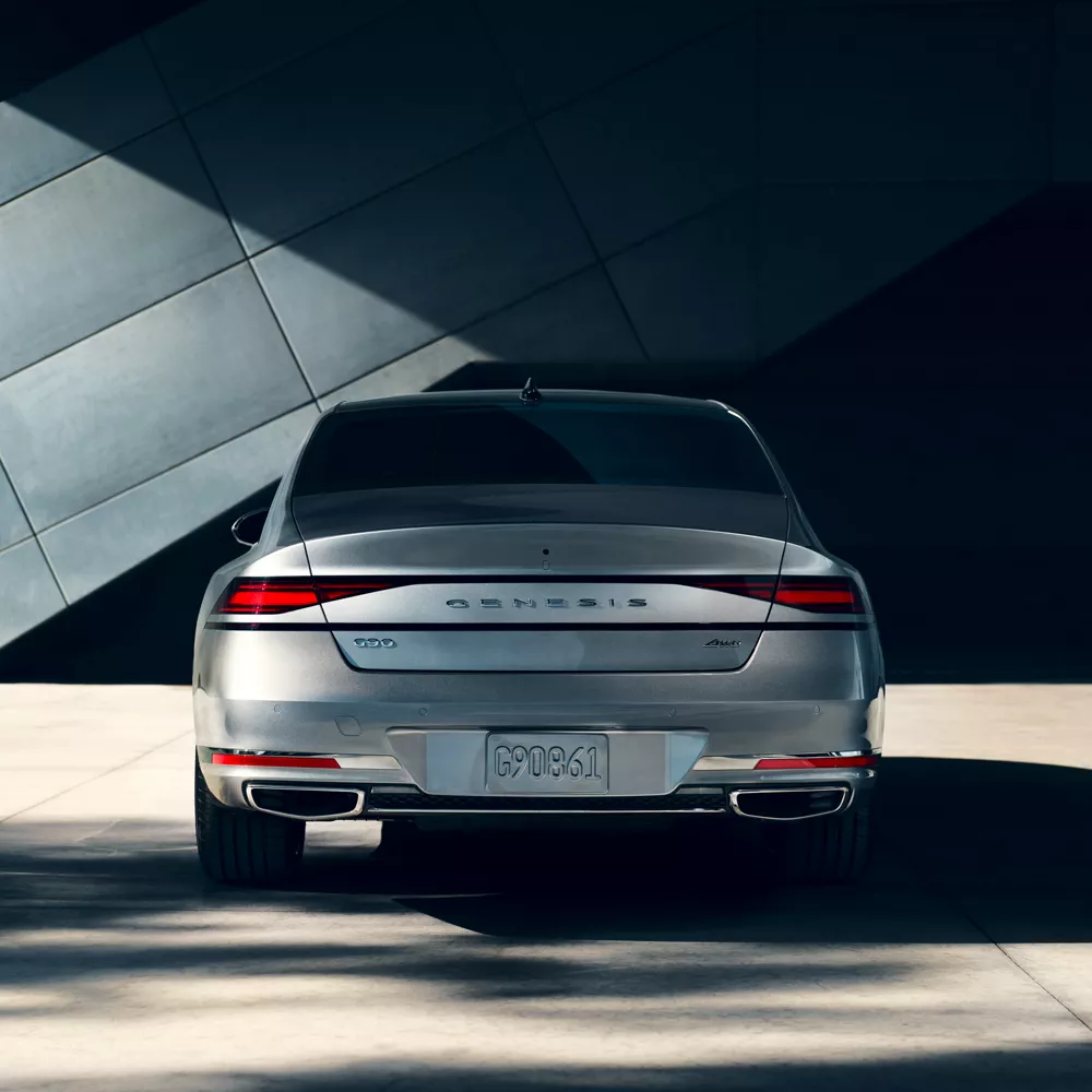 Trunk and rear tail lights of G90 parked in front of a building.