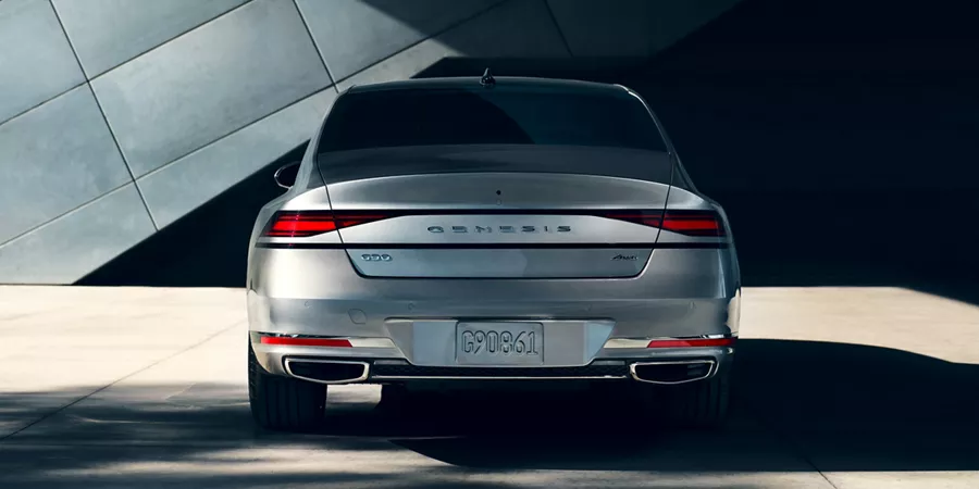 Trunk and rear tail lights of G90 parked in front of a building.