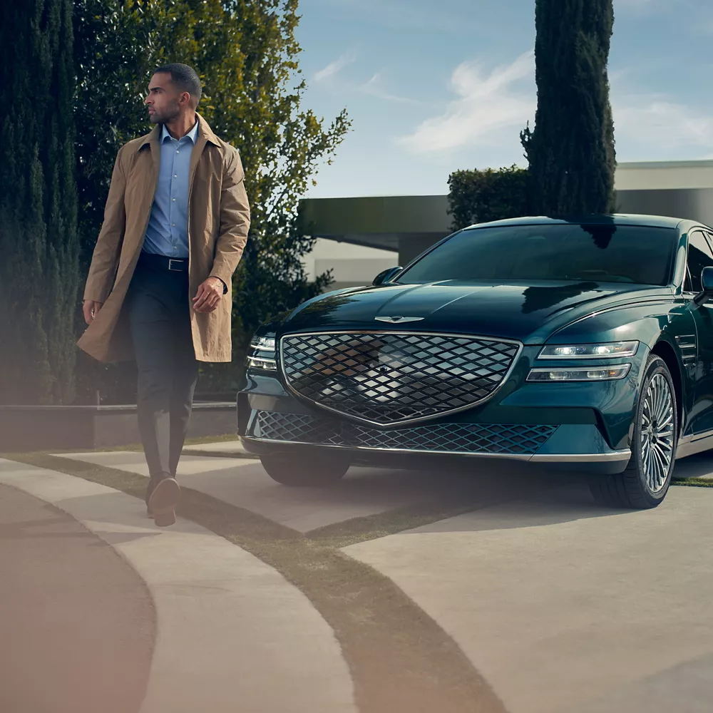 A man walking in front of the grill of the Electrified G80.