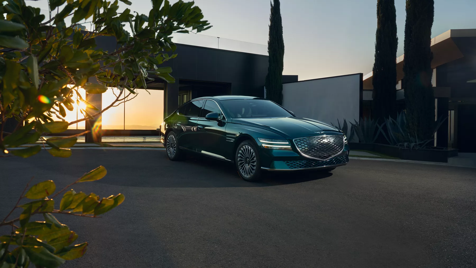 Electrified G80 sitting in the driveway with open garage behind it.