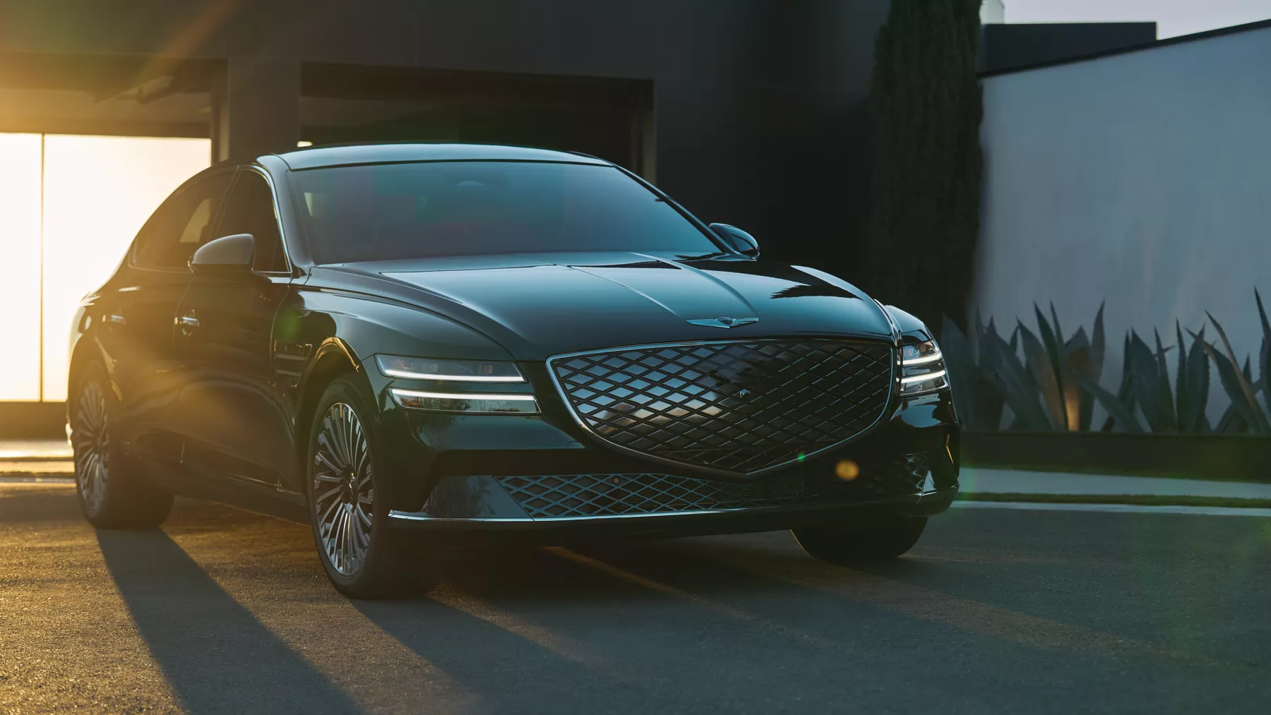 Electrified G80 sitting in driveway, with sun setting in the background.