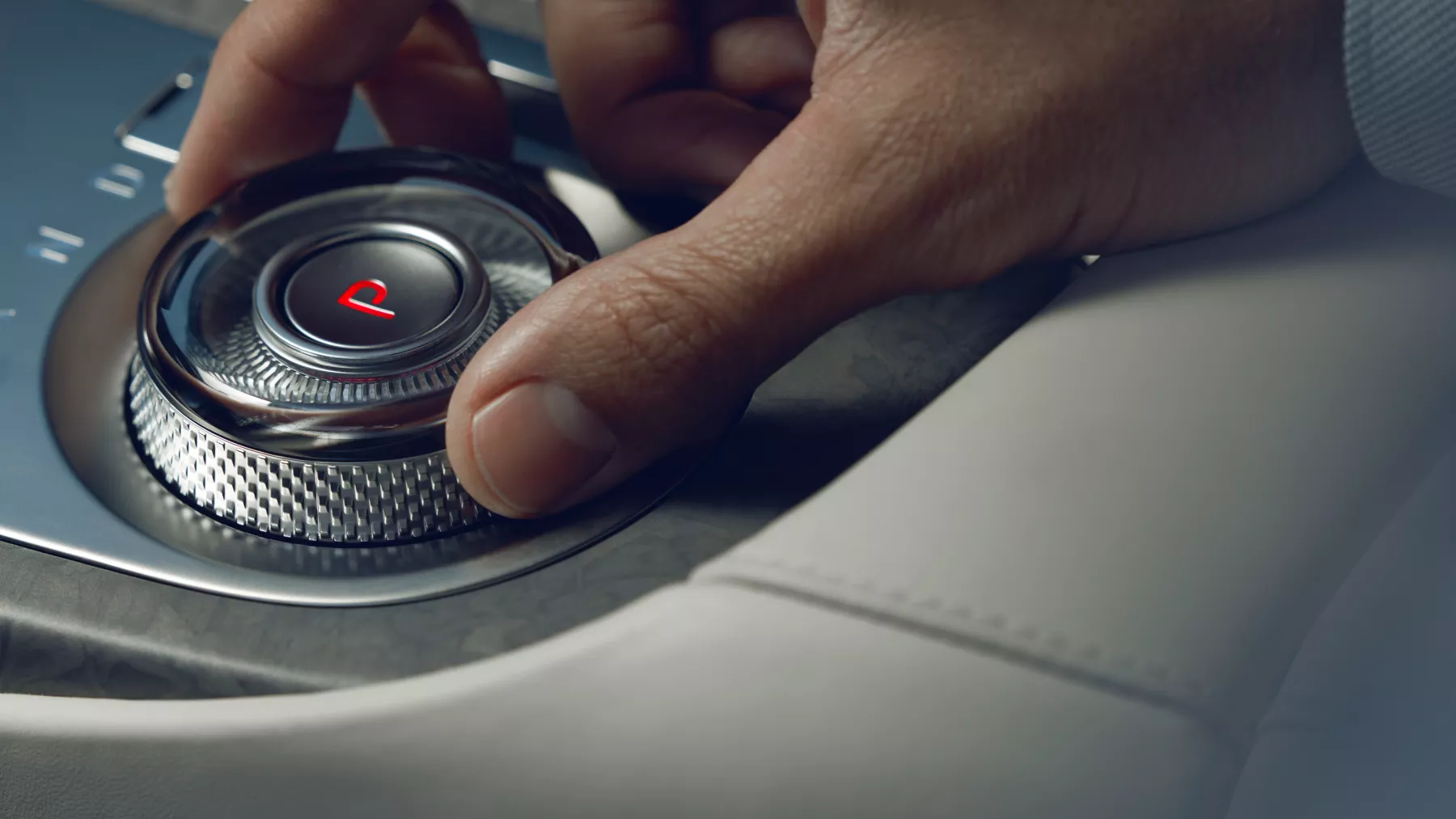 Human hand adjusting dial on Electrified G80 center console.