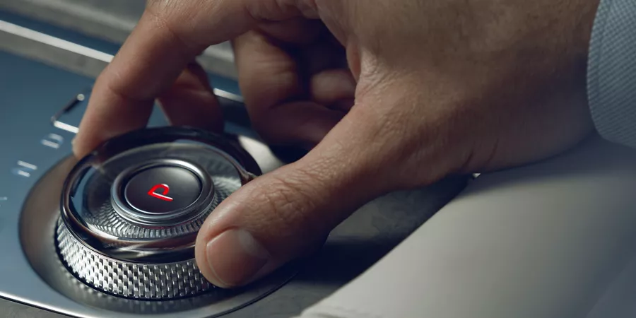 Human hand adjusting dial on Electrified G80 center console.