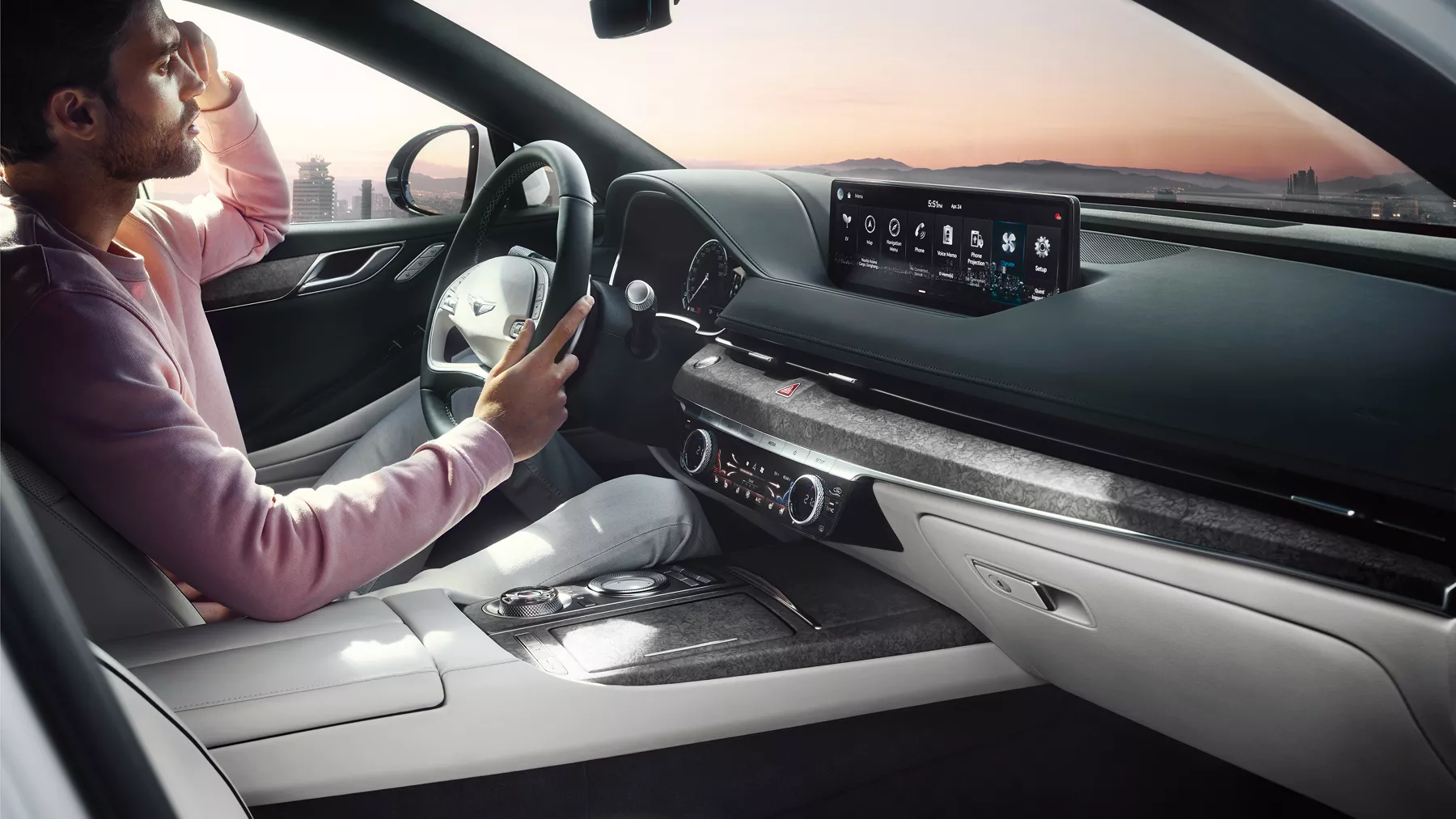 Man seated in Electrified G80 driver's seat with hand on steering wheel.