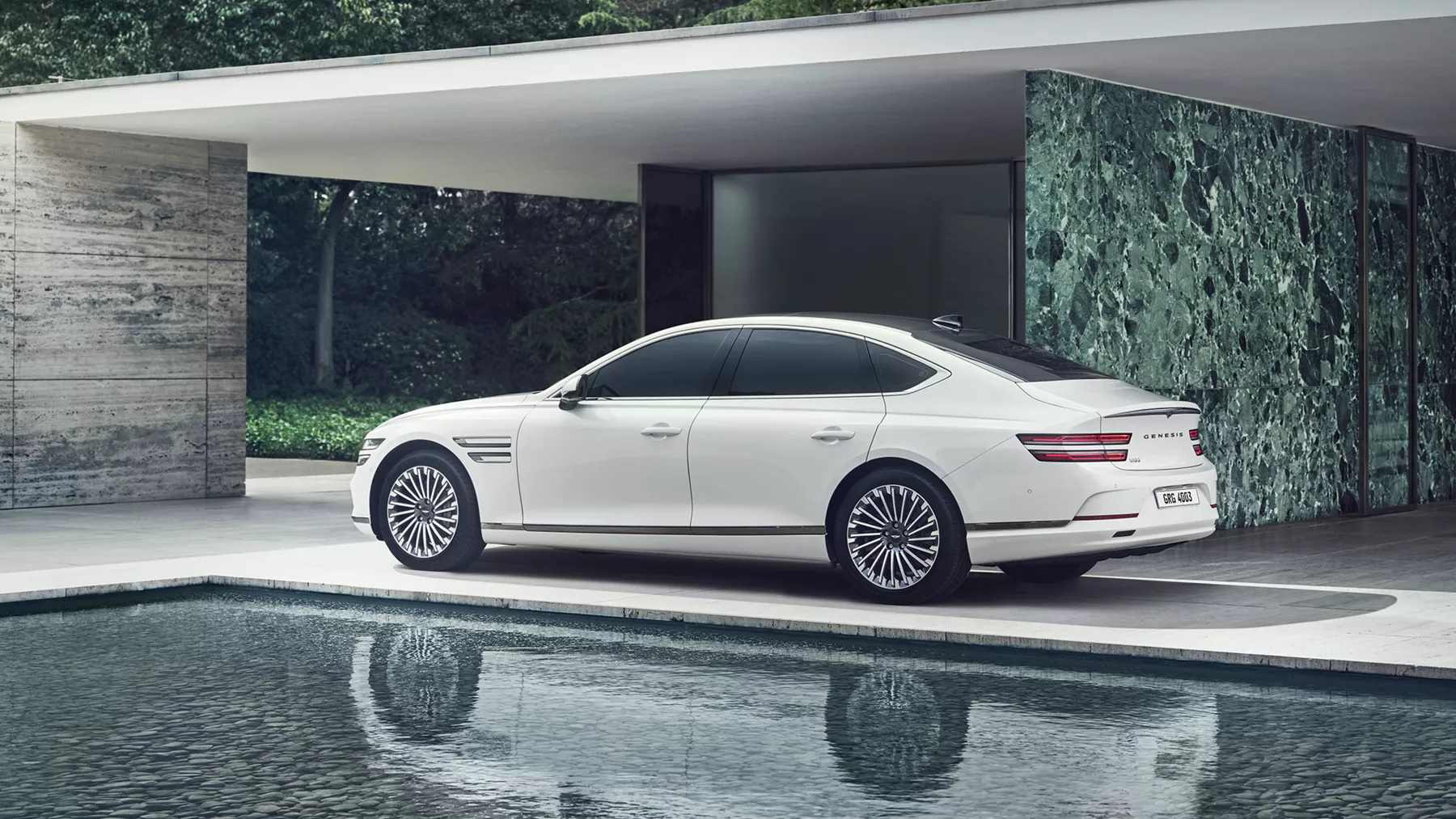 White Electrified G80 parked beside a reflecting pool.