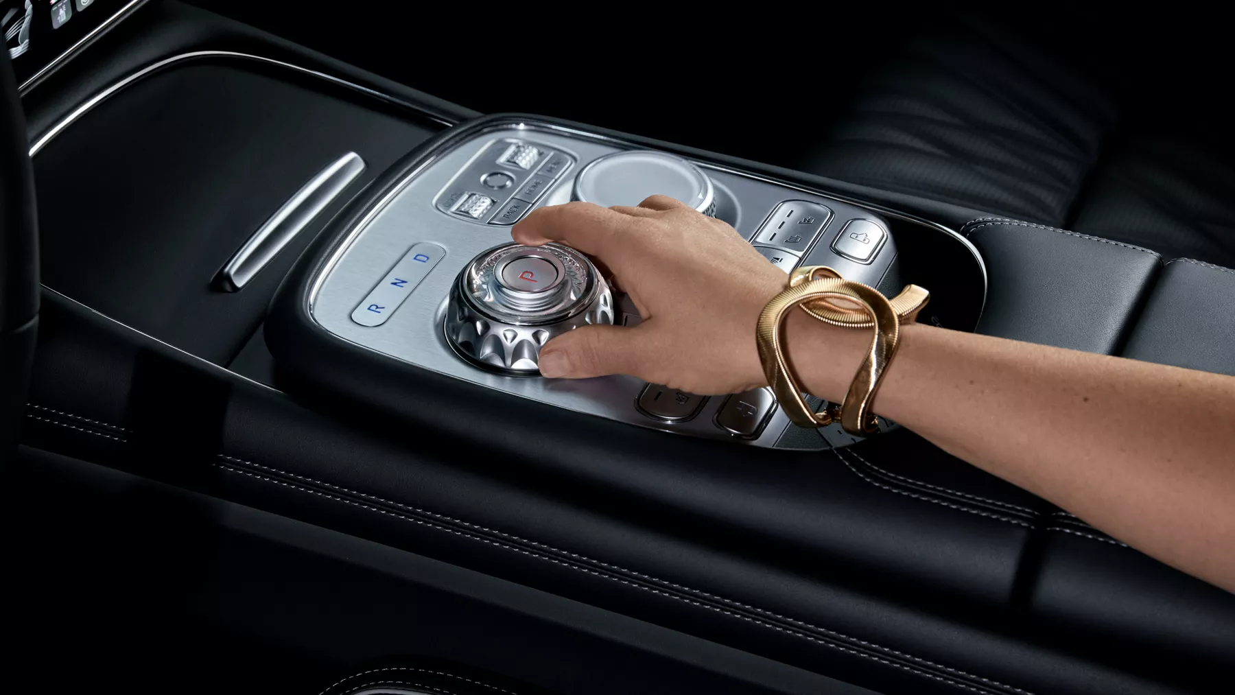 Human hand adjusting dial on G90 center console.