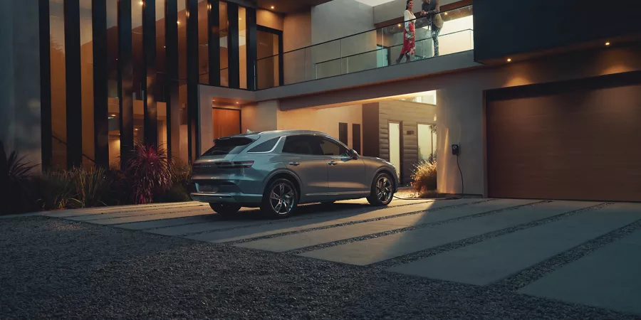 Electrified GV70 parked in the driveway of a modern house.