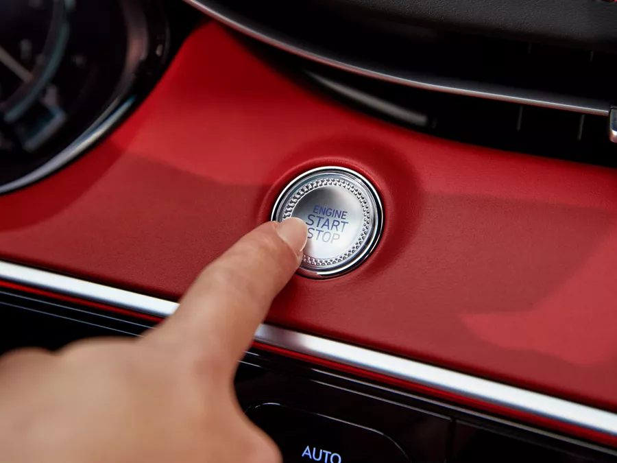 Human finger pushing button on GV70 dashboard.