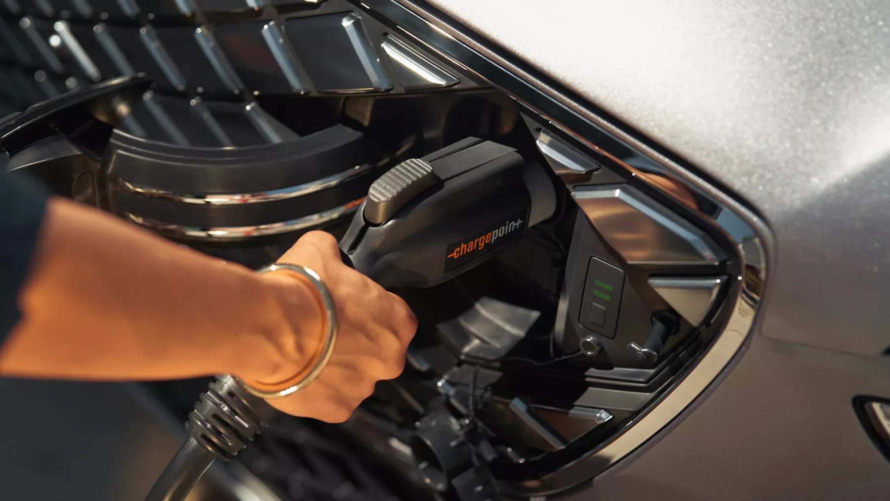 Human hand holding electric charger plugged into Electrified GV70.