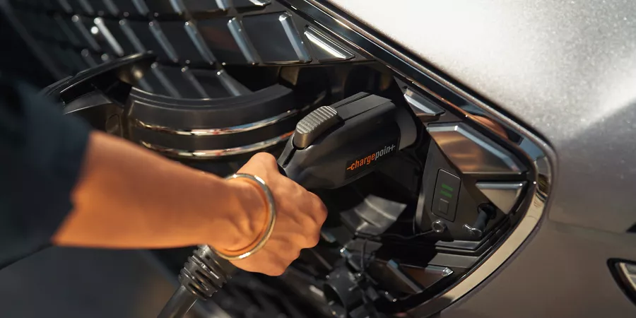 Electrified GV70에 꽂혀 있는 전기차 충전기를 잡고 있는 사람의 손.