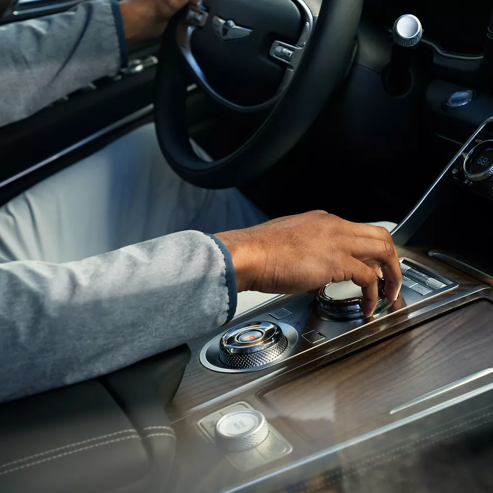 Human hand adjusting dial on GV80 center console.