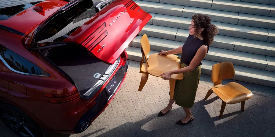 Woman packing trunk with chairs.